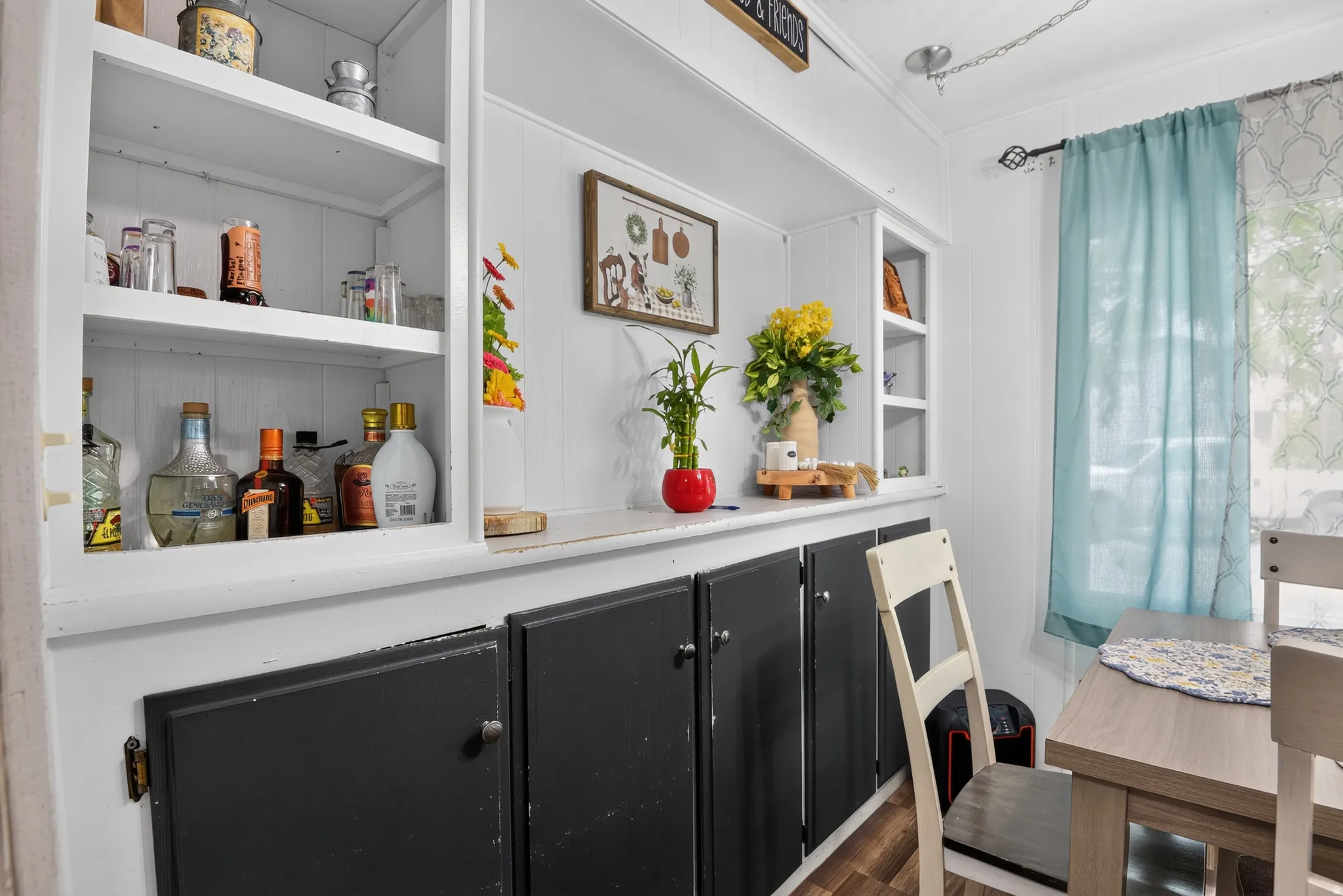 Built-in shelving with lower closed cabinetry, white wainscoting, and wood-finish flooring