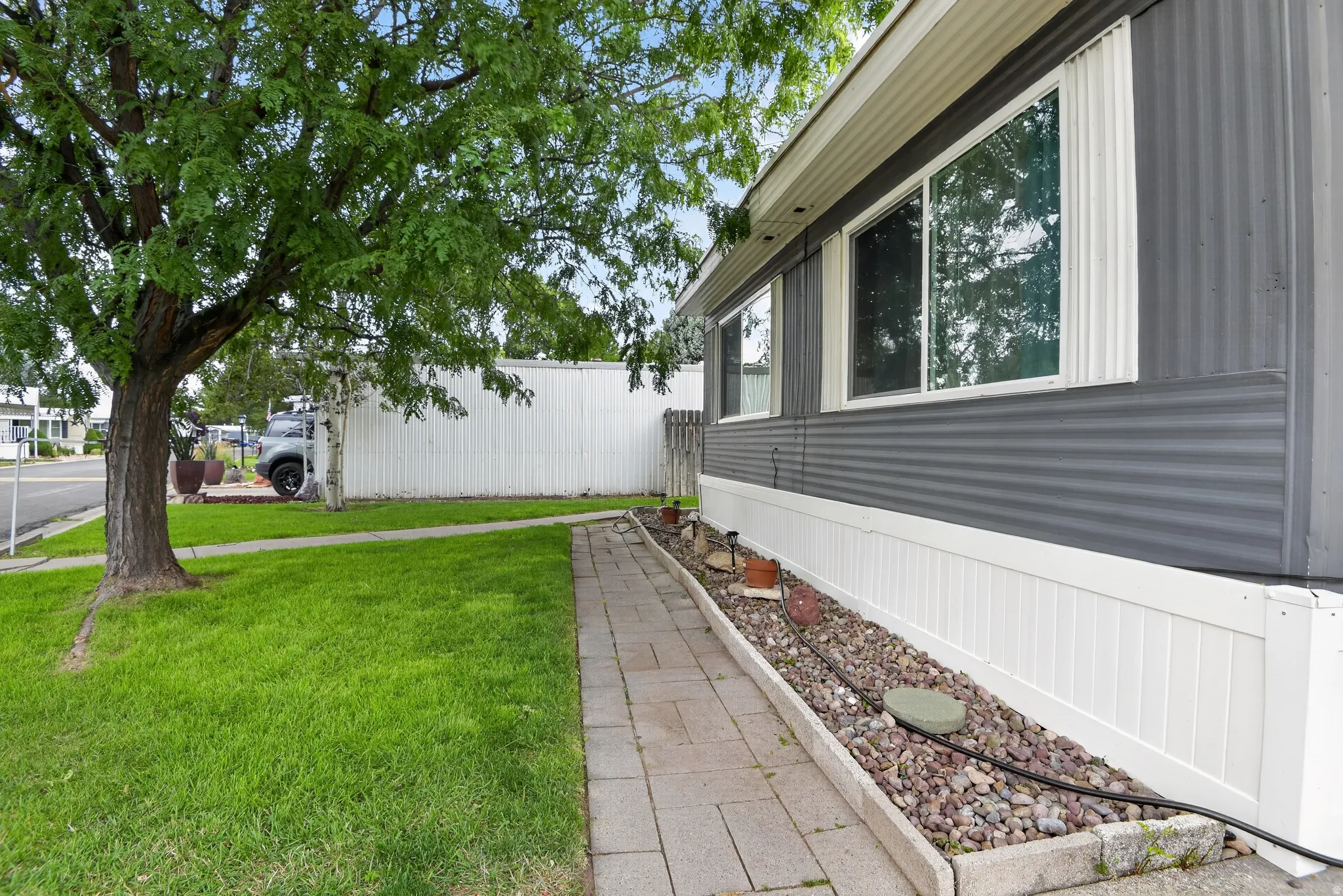 Grey corrugated siding exterior with white skirting, featuring multiple windows