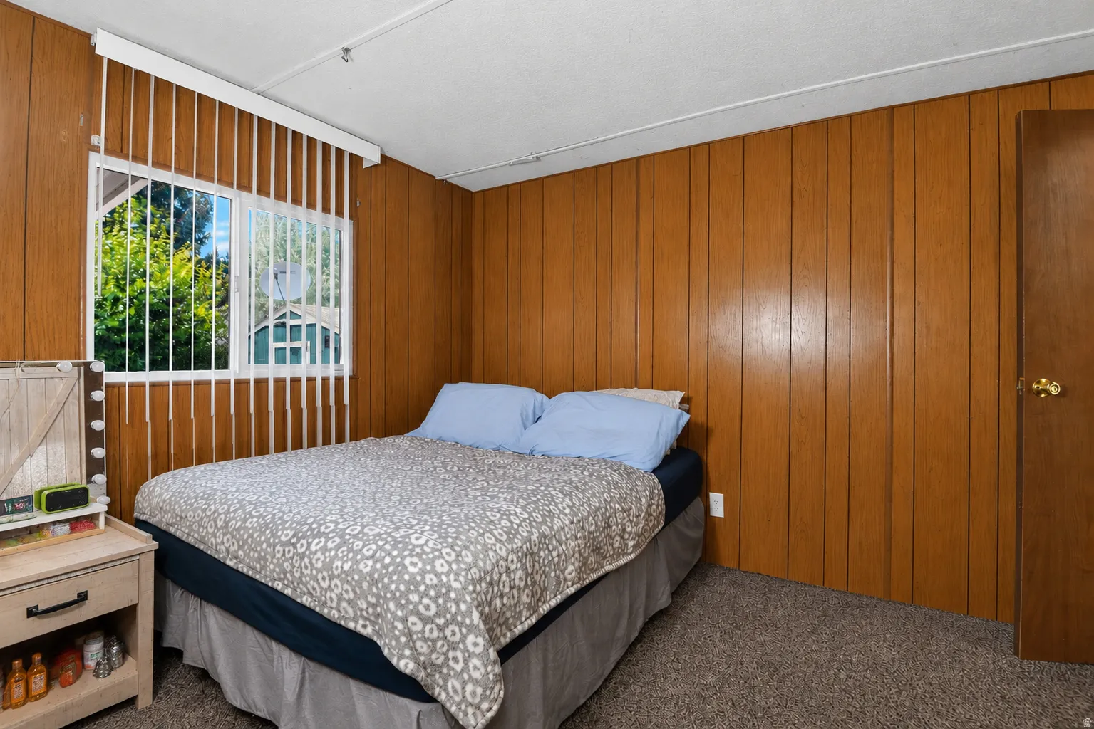Wood-paneled room featuring carpet flooring and a window with vertical blinds