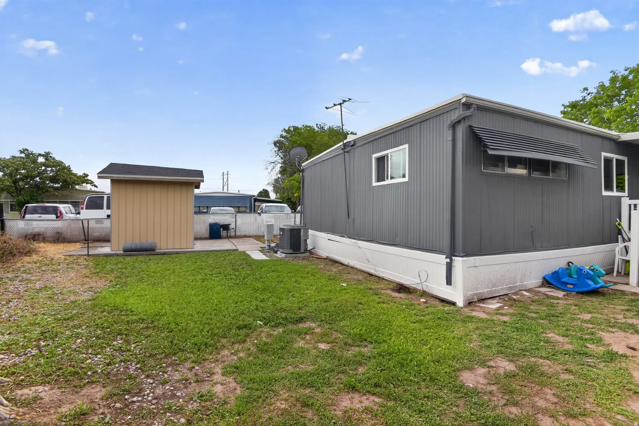 Exterior featuring grey vertical siding, white trim, and a horizontal louvered awning