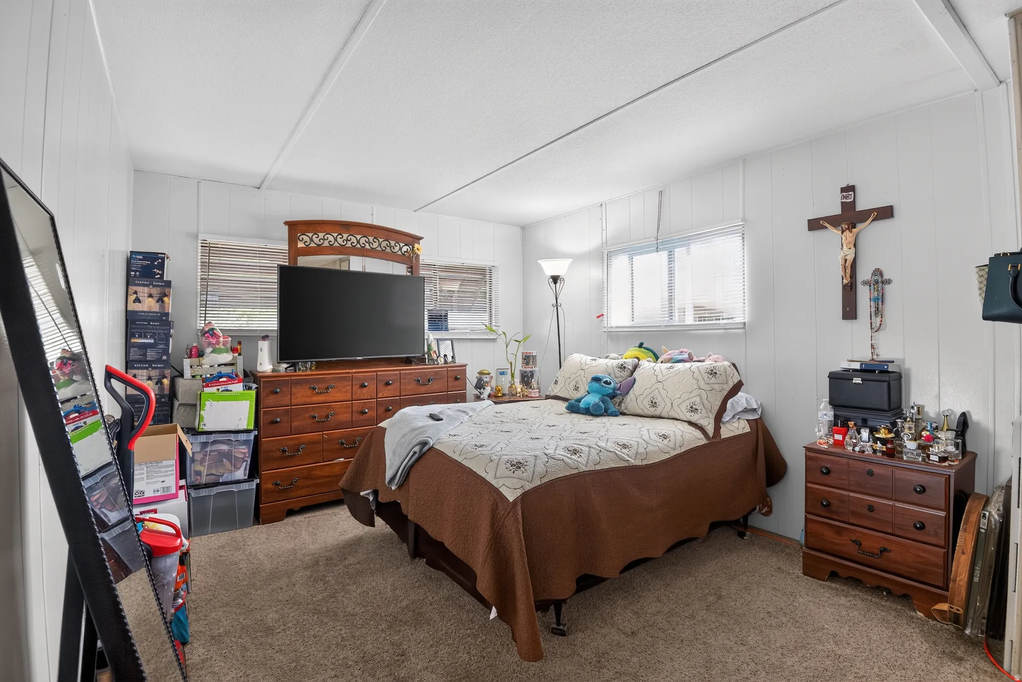 Carpeted room featuring white vertical paneling and two windows with horizontal blinds