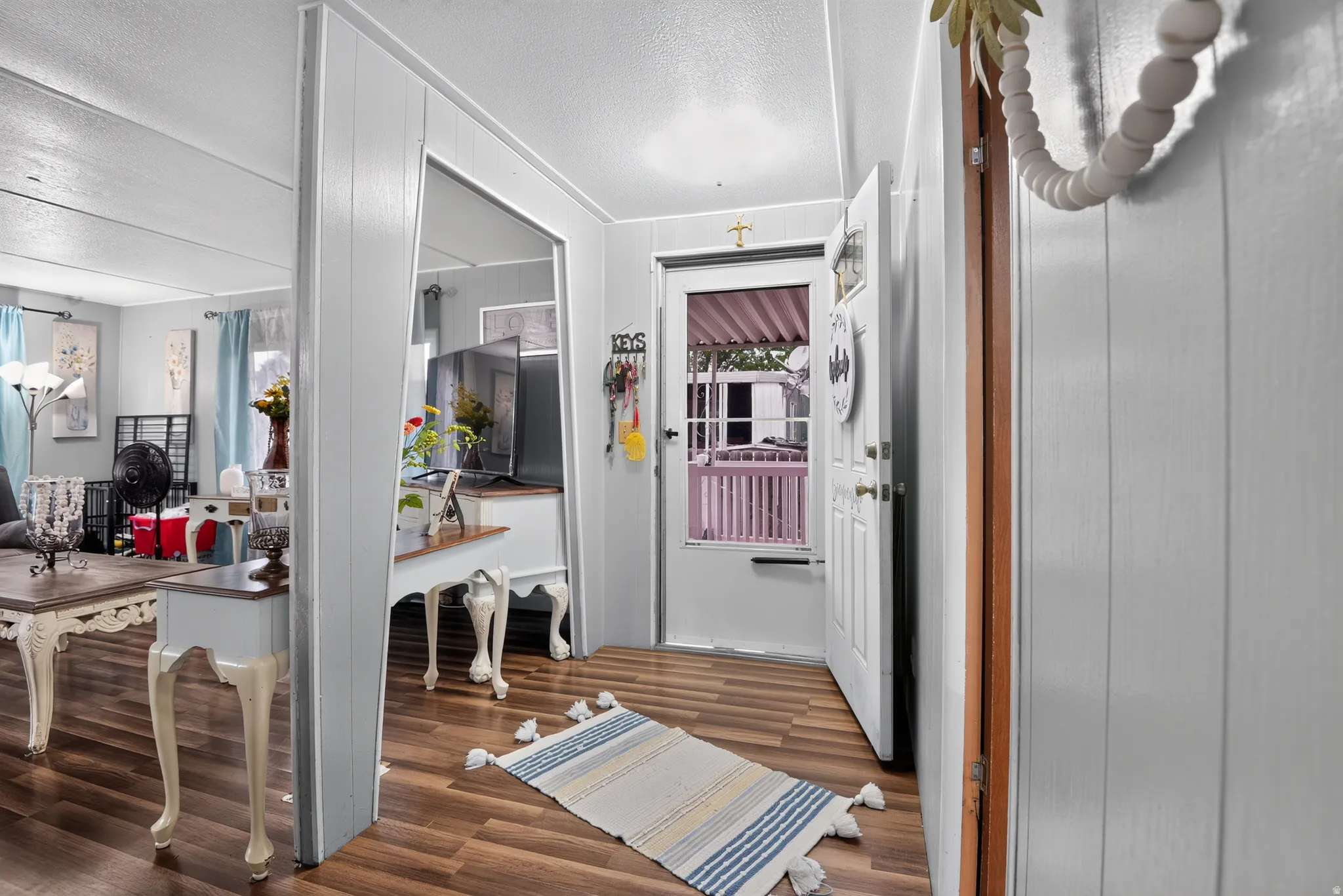 Interior entry with wood-finish flooring, white paneled walls, and a white entry door with a frosted glass insert