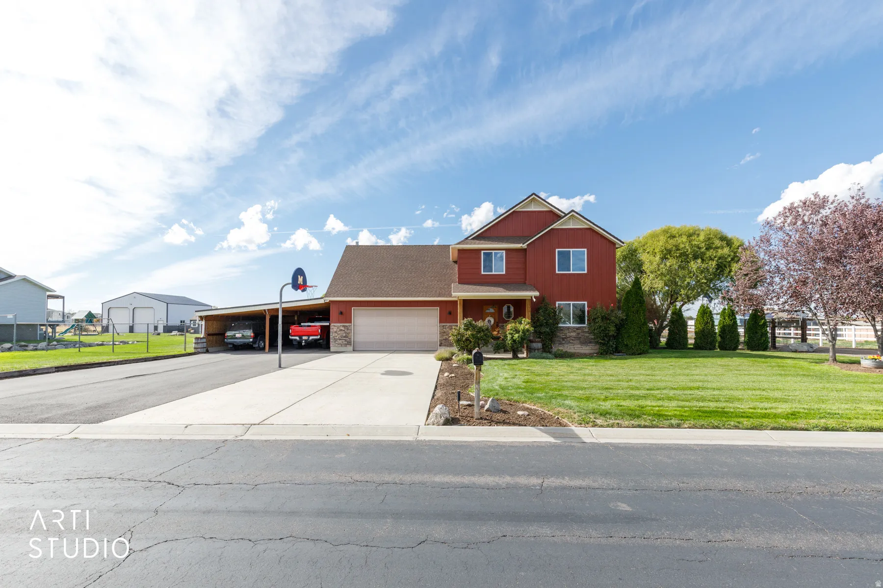 Red siding exterior with stone accents, a double-car garage, and an attached carport