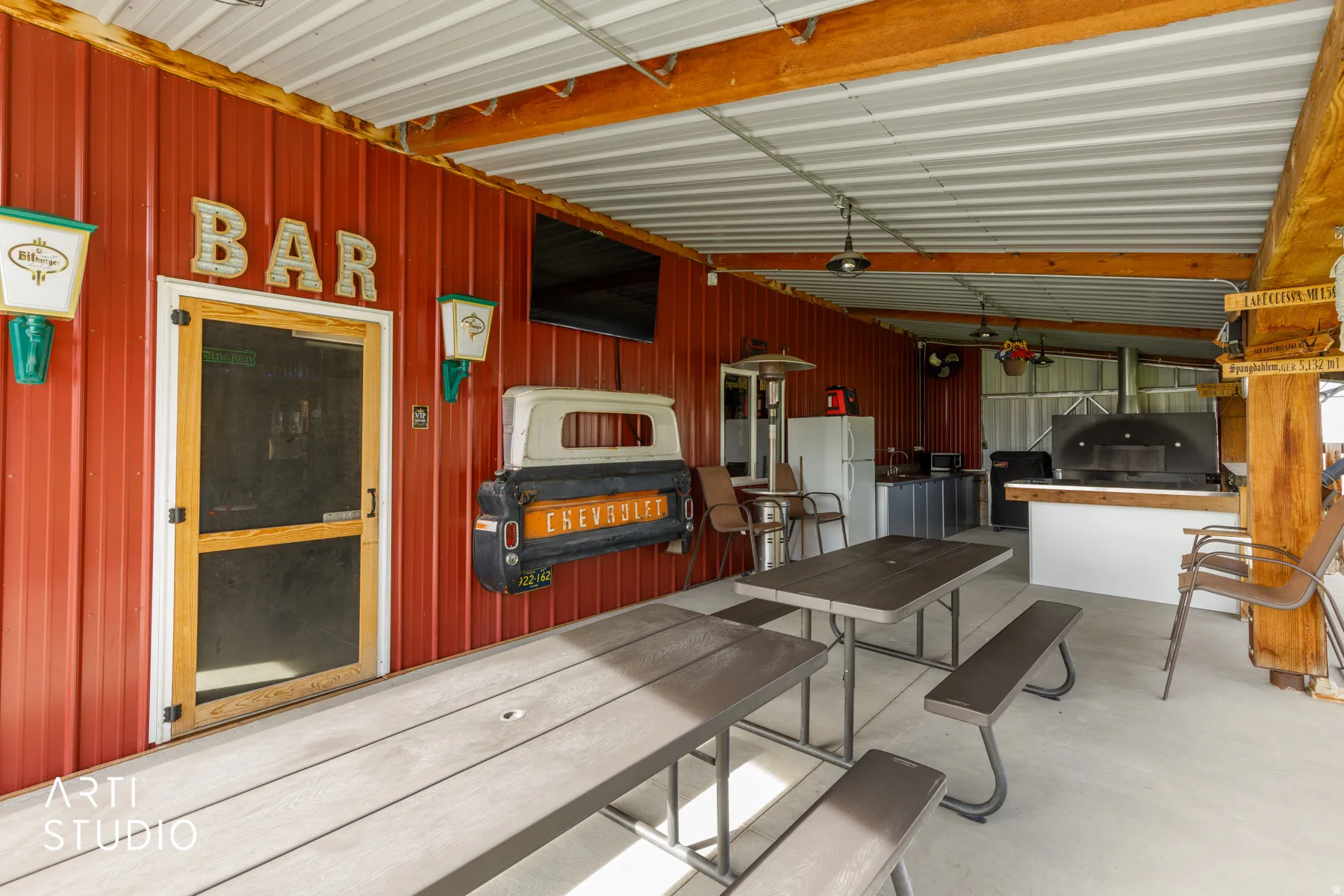 Covered outdoor entertainment area featuring a red corrugated metal wall and a metal ceiling
