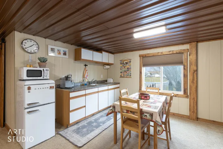 Compact kitchen area featuring wood-finish cabinetry, granite-style countertops, white paneling, and a wood-paneled ceiling