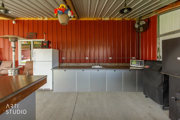Outdoor kitchen area featuring a corrugated metal ceiling and red panel wall