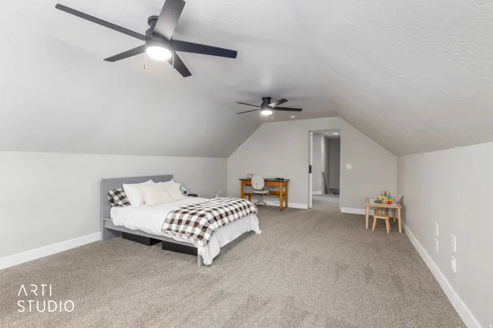 Spacious room featuring vaulted ceilings, plush carpeting, contemporary ceiling fans with integrated lighting, and neutral wall tones