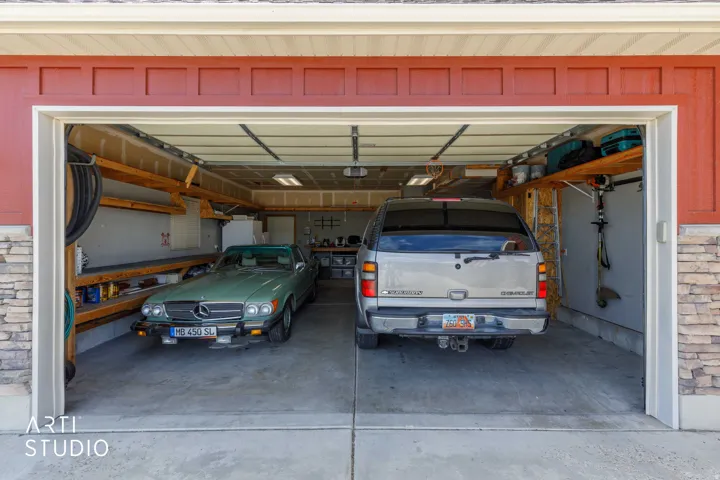 Two-car garage featuring concrete flooring, built-in shelving, overhead lighting, and a paneled garage door