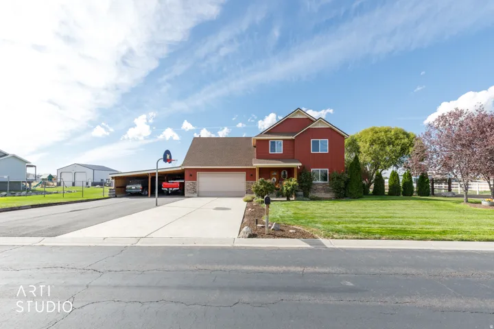 Red siding exterior with stone accents, a double-car garage, and an attached carport