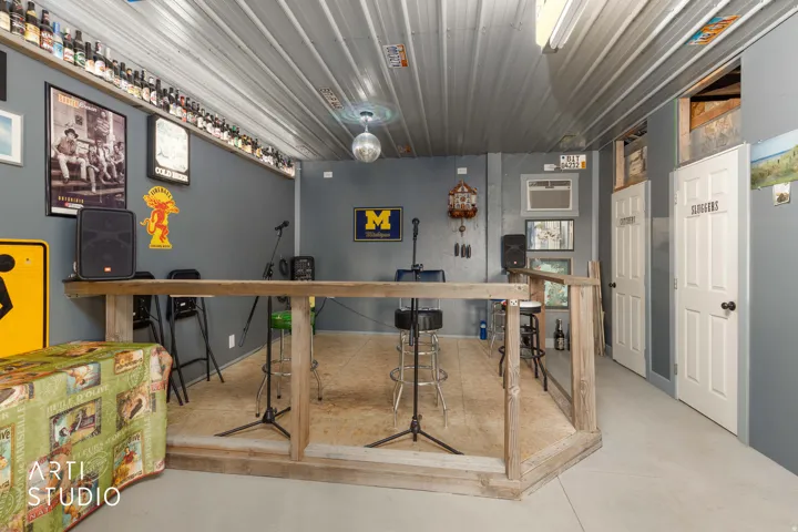 Interior space featuring a raised wood-framed stage, corrugated metal ceiling, and two white panel doors