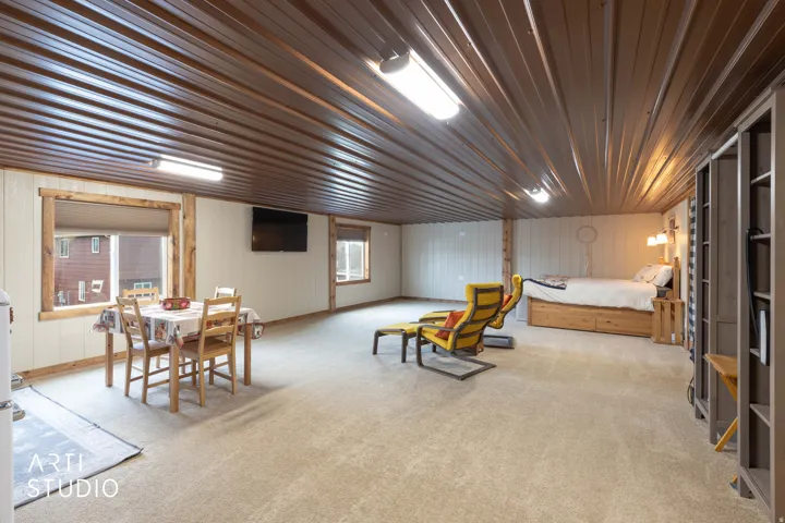 Spacious room with a brown corrugated metal ceiling, light-toned carpeting, and white wall paneling