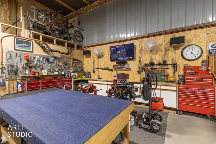 Dedicated workshop space featuring ample built-in storage, a large work surface, and overhead shelving