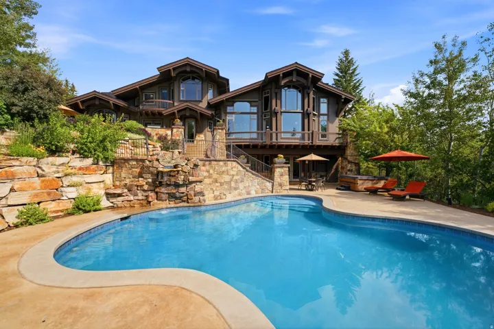 Curved swimming pool with a stone retaining wall and integrated waterfall feature