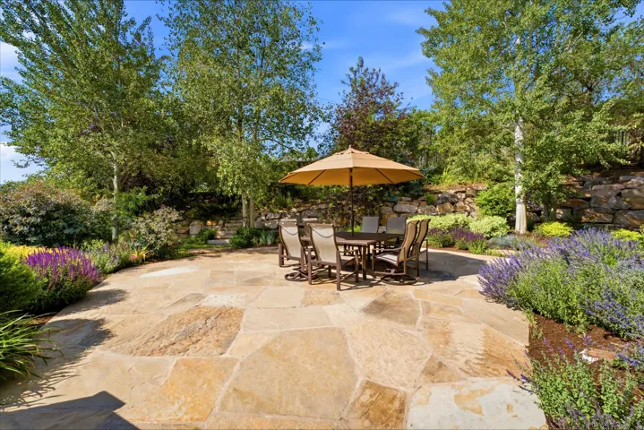 Expansive flagstone patio with surrounding mature trees and lush landscaping