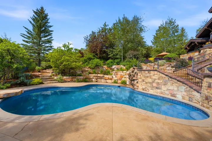 Freeform swimming pool featuring a natural rock waterfall and integrated diving platform