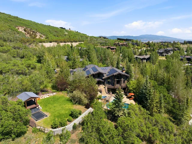 Elevated property featuring a multi-story residence with solar panels, a tiered outdoor entertaining area, and a swimming pool