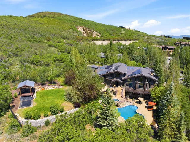 Mountain-style residence featuring a multi-level exterior, an outdoor swimming pool, and a stone patio