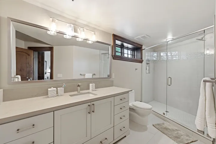 Contemporary bathroom featuring a spacious glass-enclosed shower with white subway tile and a decorative wave accent