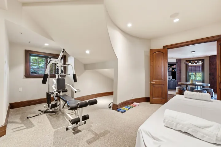 Carpeted recreation room featuring a window with dark wood trim, recessed lighting, and a wood-paneled doorway opening into another room