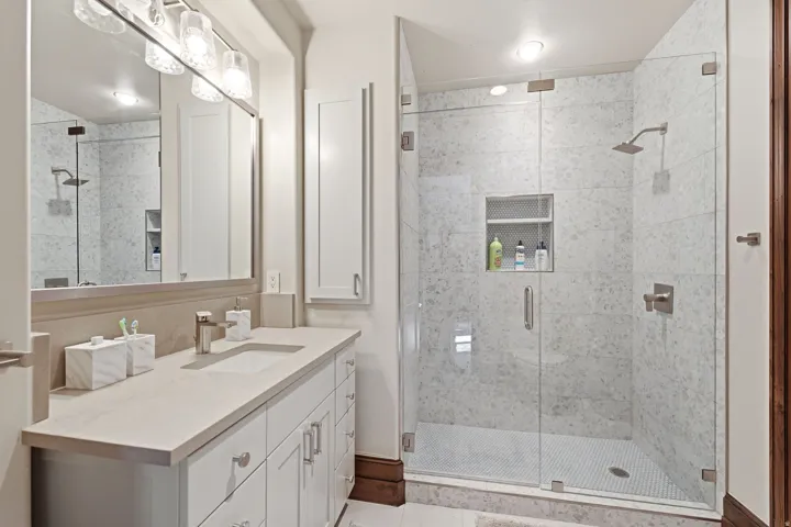 Spacious bathroom featuring a glass-enclosed shower with white tiled walls and a recessed niche