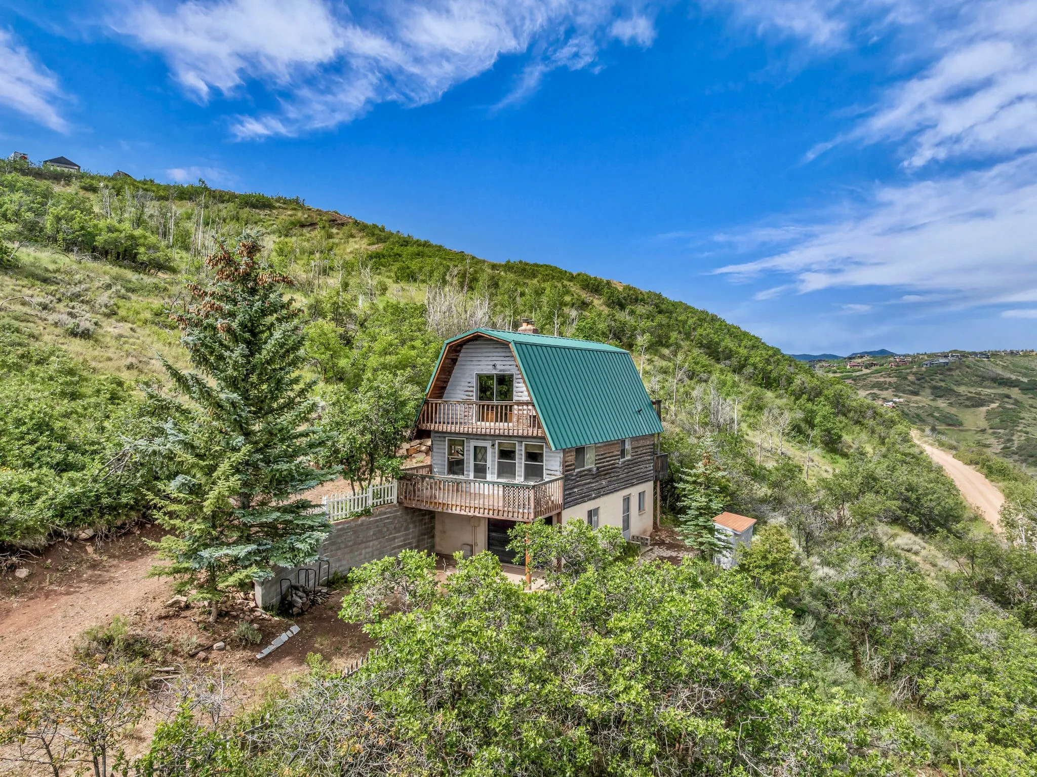 A green metal gable roof, nestled on the hill top.