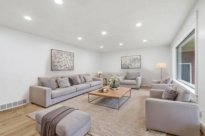 Spacious living area featuring recessed lighting, large window, wood-finish flooring, and a neutral color palette