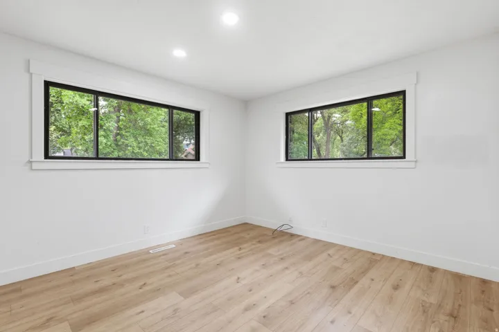 Room featuring two horizontal windows with black frames, white trim, and white walls