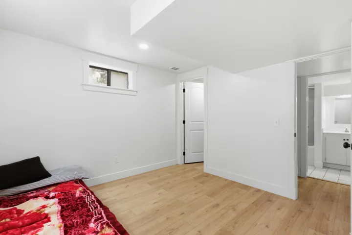White-painted interior space with wood-finish flooring, a single window, and a recessed ceiling light