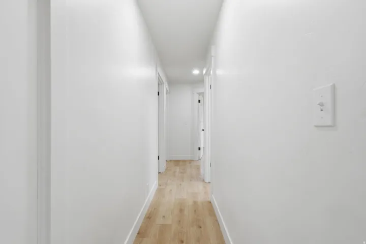 Hallway featuring wood-finish flooring, recessed lighting, and white walls