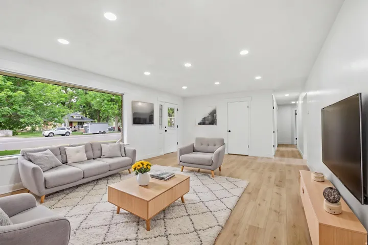 Spacious living area featuring light wood-finish flooring, recessed lighting, and a large picture window