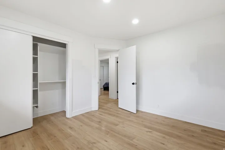 Bright interior room featuring wood-finish flooring, recessed ceiling lighting, and crisp white walls
