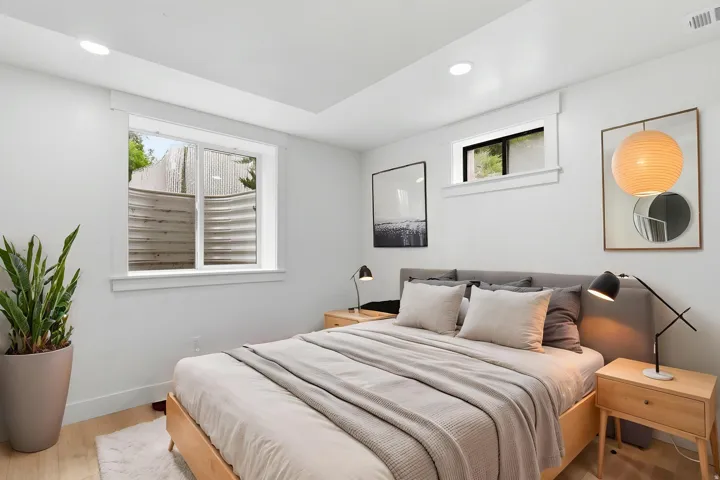 Bedroom featuring light wood-finish flooring, recessed lighting, and a window well providing natural light