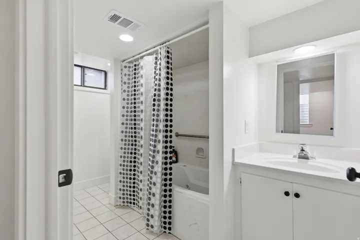 Bathroom featuring a single vanity with an integrated sink, a built-in mirror, and overhead lighting