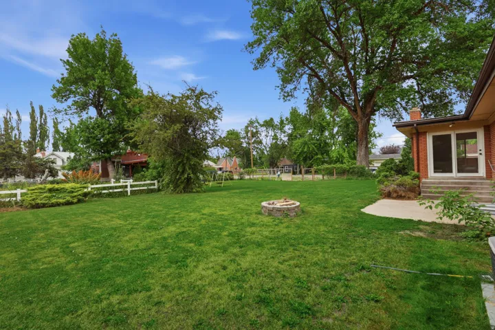 Expansive lawn area featuring a stone fire pit and mature trees