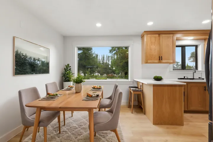 Open-concept dining area featuring light wood-finish flooring, recessed lighting, and a large window
