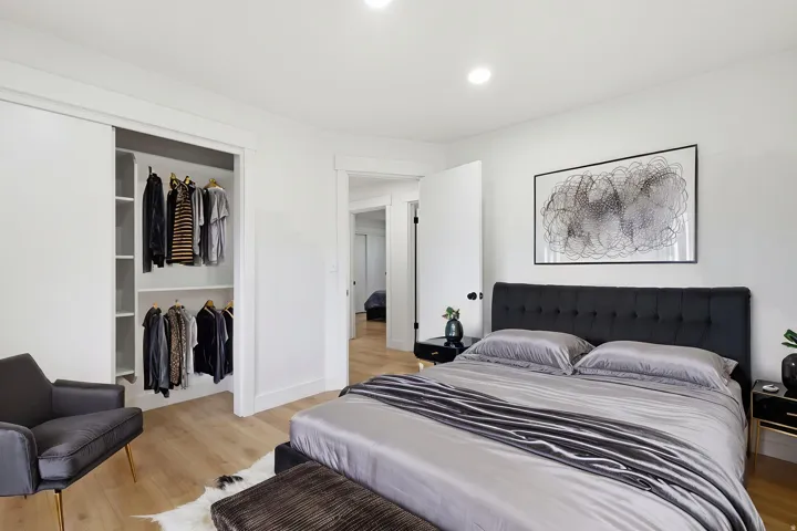 Bedroom featuring wood-finish flooring and a closet with sliding doors and custom shelving