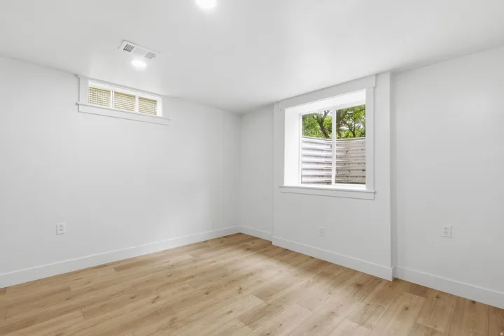 Bright room featuring wood-finish flooring, white walls, recessed ceiling lighting, and two windows