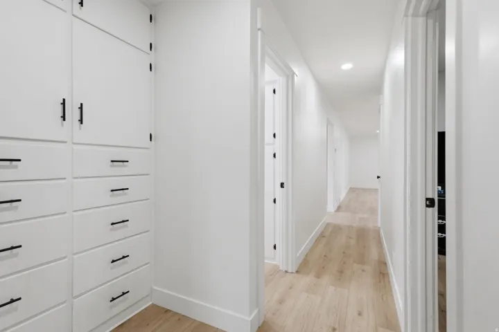 Hallway with light wood-finish flooring, recessed lighting, and white baseboards