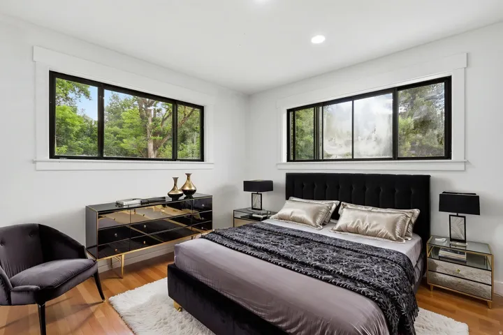 Bedroom featuring hardwood-finish flooring and multiple windows with black frames