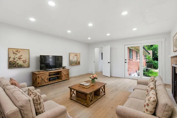 Recessed lighting illuminates this bright living area featuring wood-finish flooring