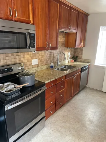 Kitchen featuring warm-toned cabinetry, granite-finish countertops, and a mosaic tile backsplash