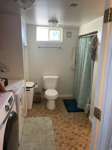 Bathroom with square tile flooring, a window, and a shower area