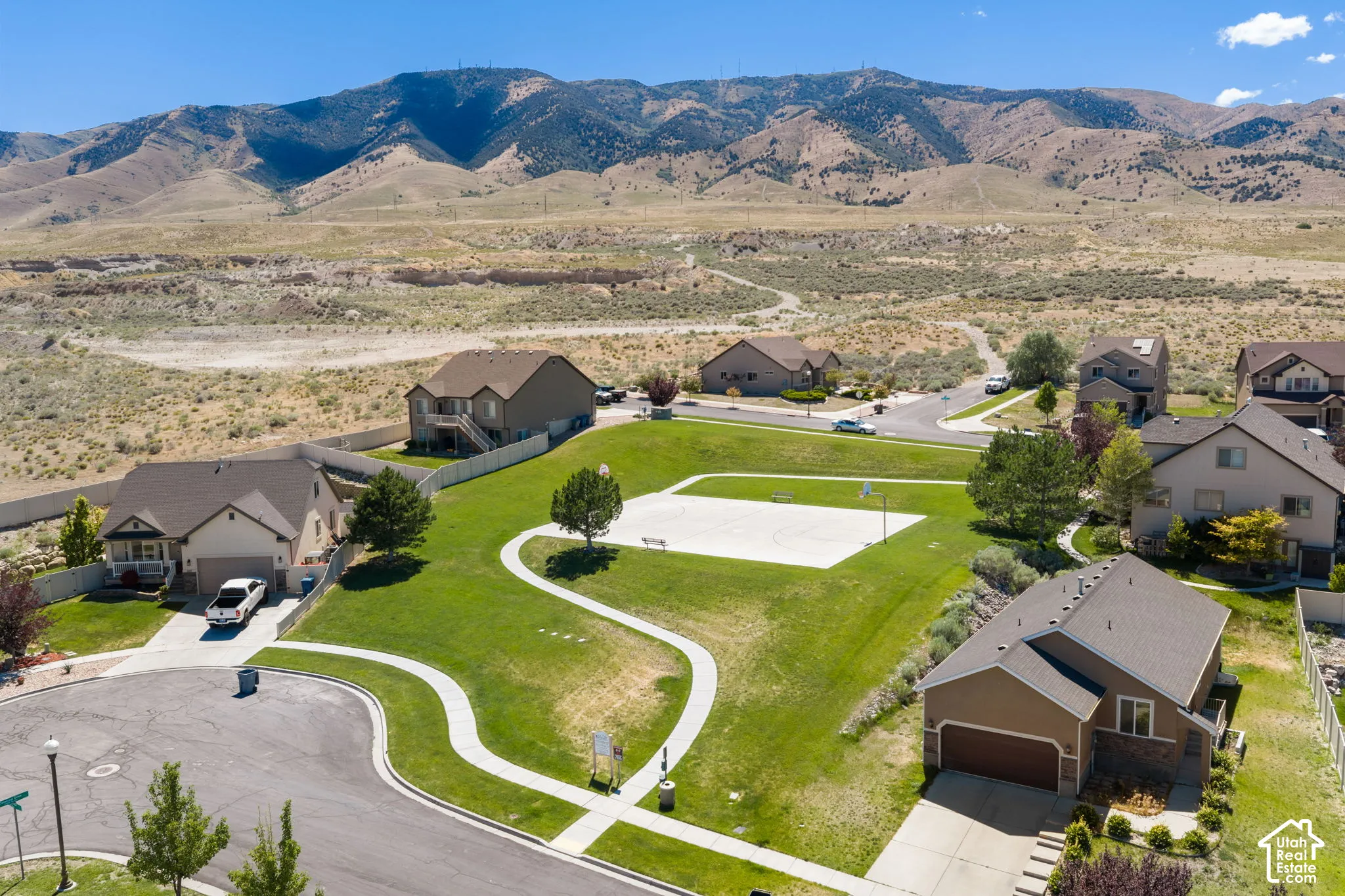 Residential neighborhood featuring an expansive green space with a paved pathway and basketball court