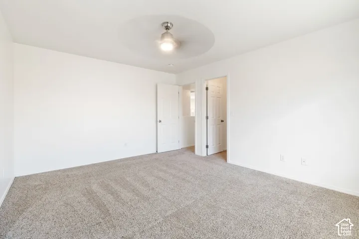 Neutral-toned carpeting paired with white walls, featuring a ceiling fan with integrated lighting