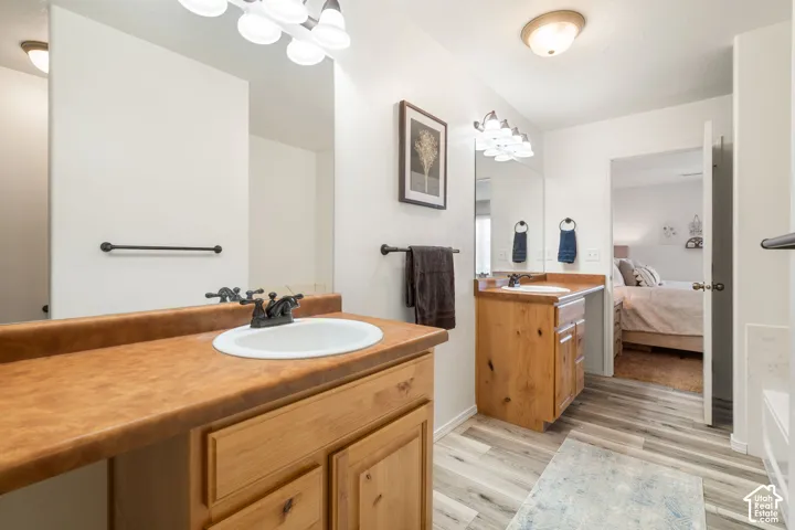 Dual vanity with wood-finish cabinetry and integrated sinks, complemented by a large wall-mounted mirror and overhead lighting