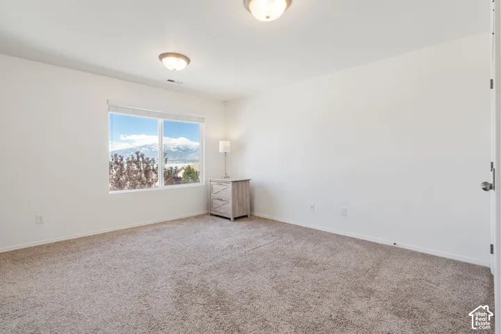 Bright room featuring a large window with mountain and lake scenery, neutral carpeting, and a flush mount ceiling light fixture