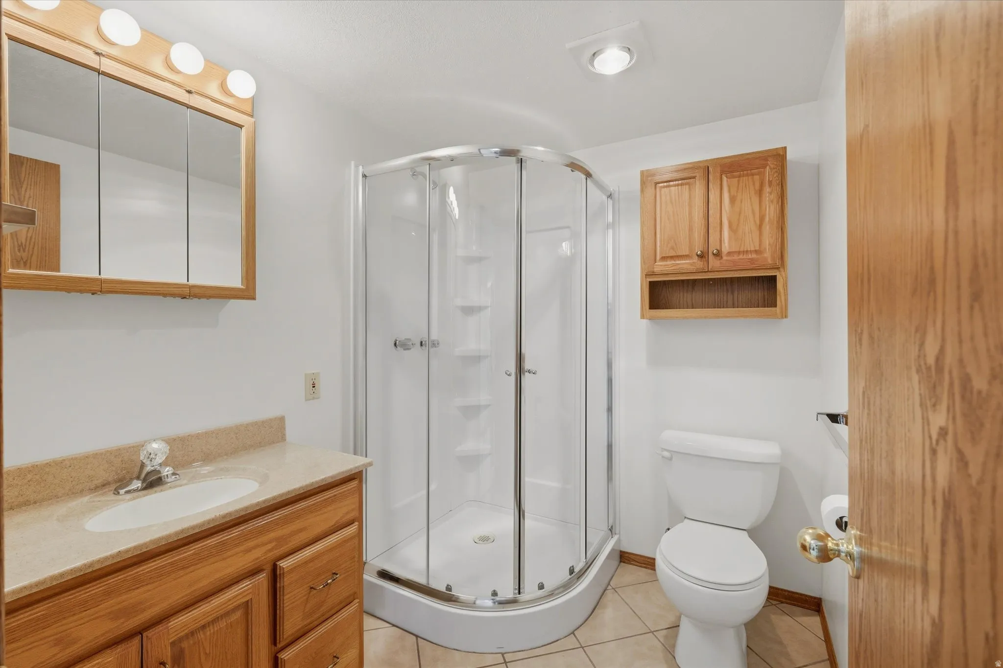 Bathroom featuring a corner shower enclosure with clear glass, a vanity with wood-finish cabinetry, and a light-colored countertop