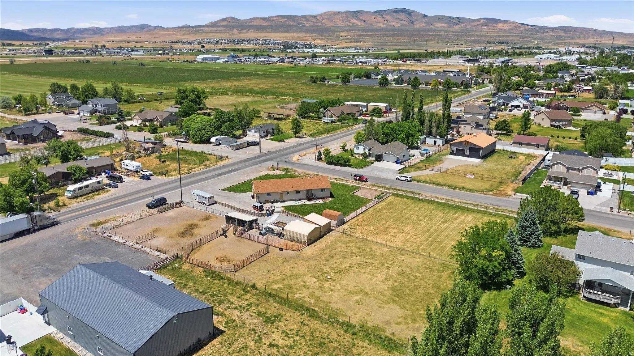 Expansive property featuring a prominent metal-roofed building, multiple fenced enclosures, and a large open field