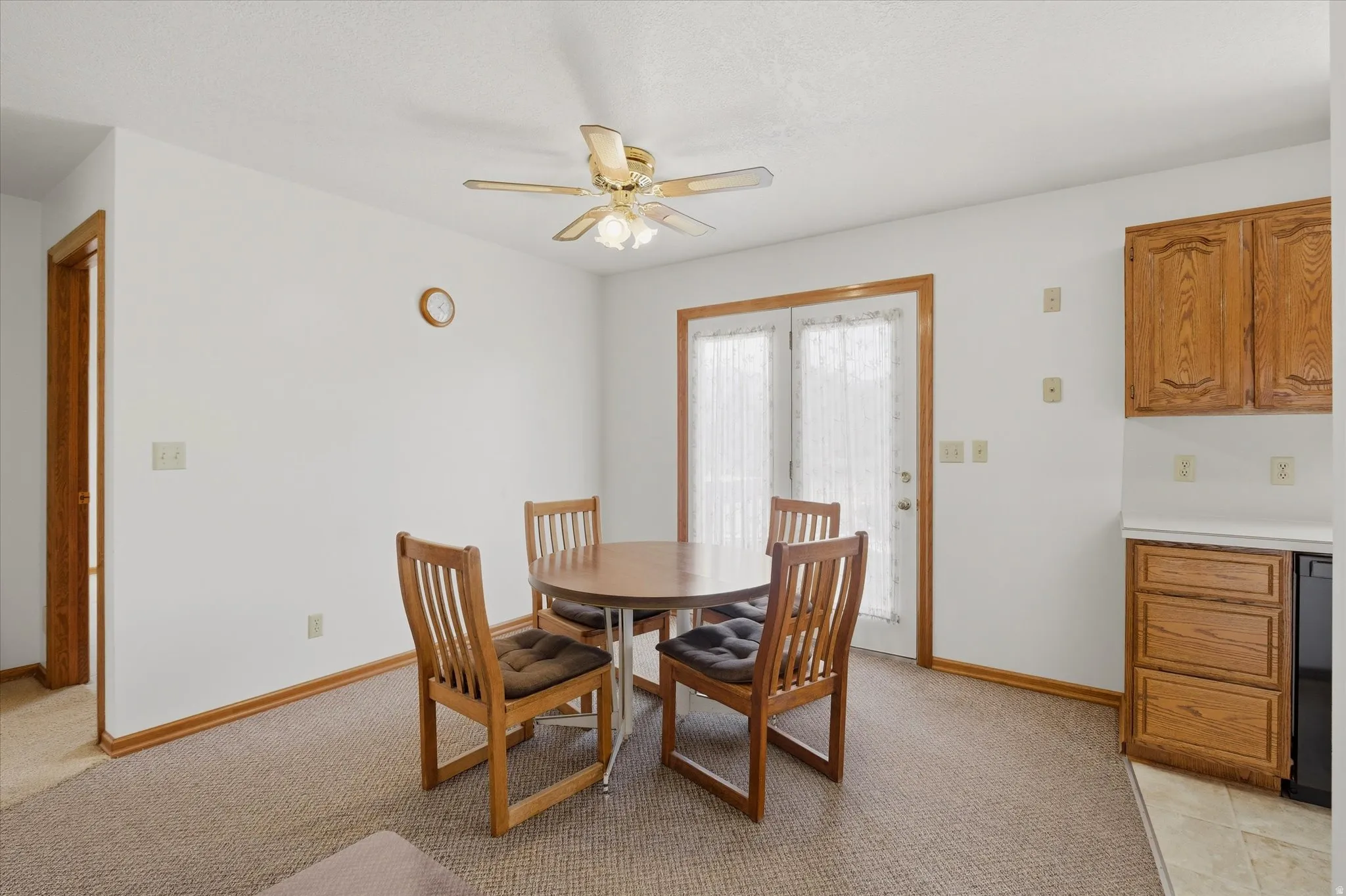 Dining area featuring a ceiling fan with integrated lighting, a doorway with wood trim, and double French doors with sheer curtains