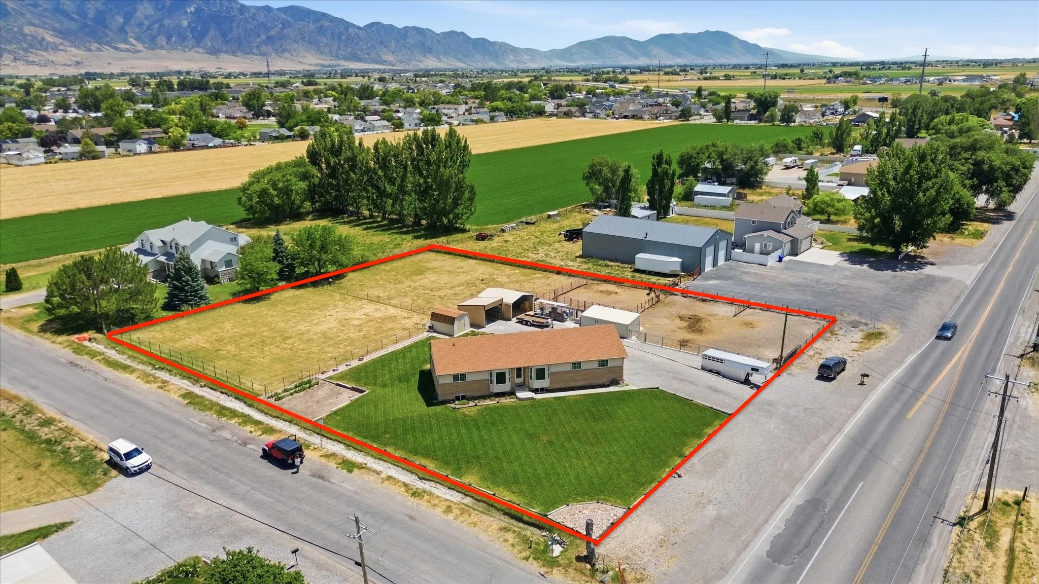 Expansive property featuring a single-story residence, substantial land area, mountainous backdrop, and established roadway access